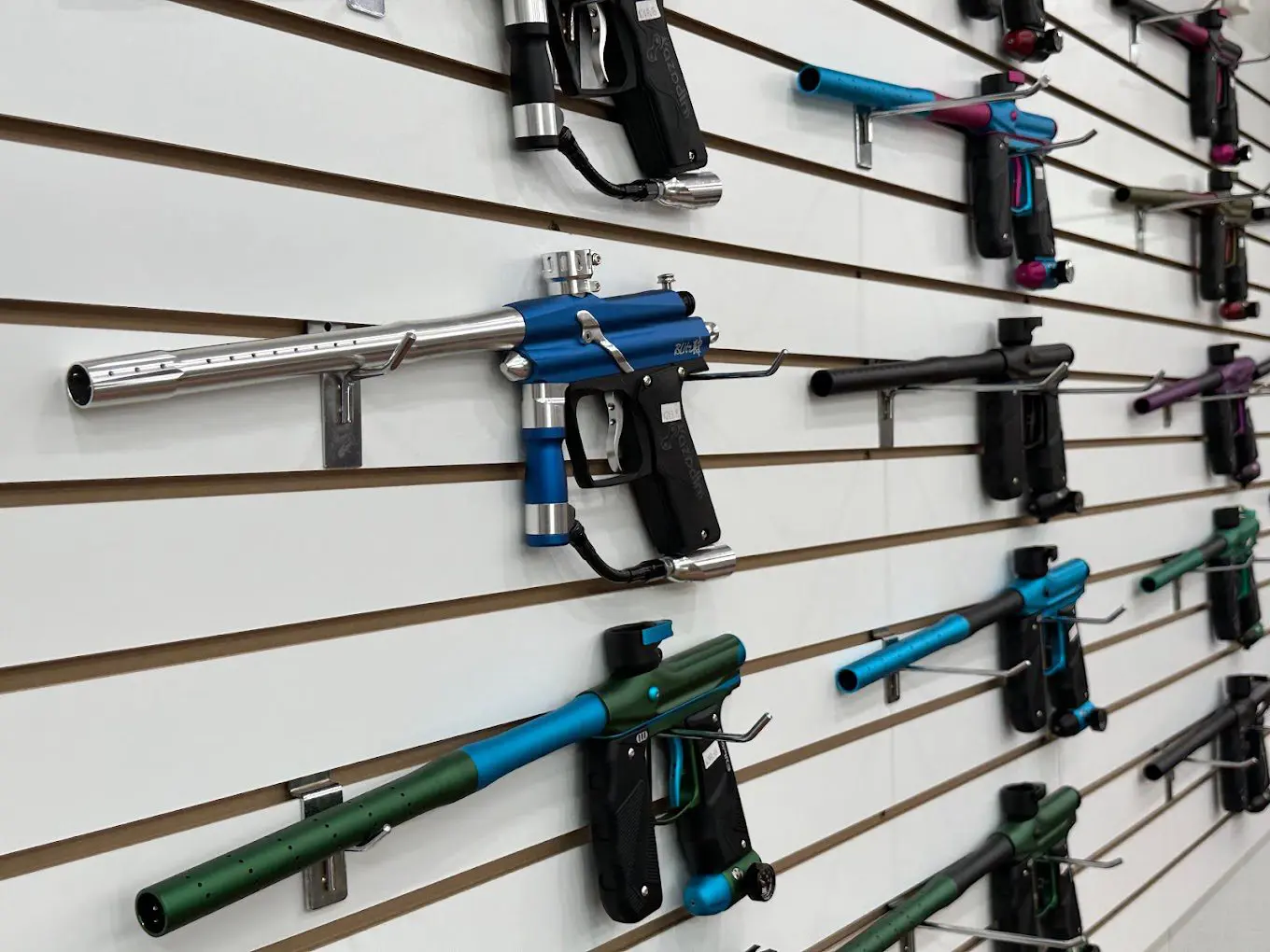 A wall with many different types of guns hanging on it.